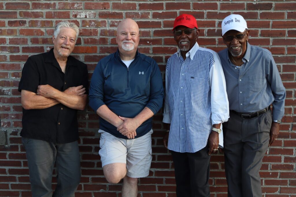 sumpin doo band standing in front of a brick wall