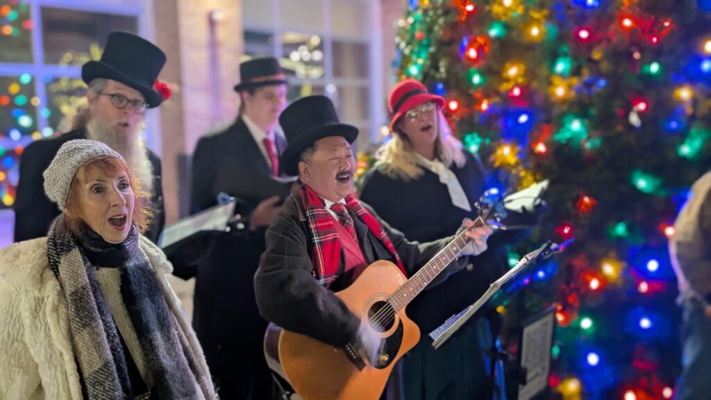 top hat carolers singing next to the christmas tree at jingle in the junction