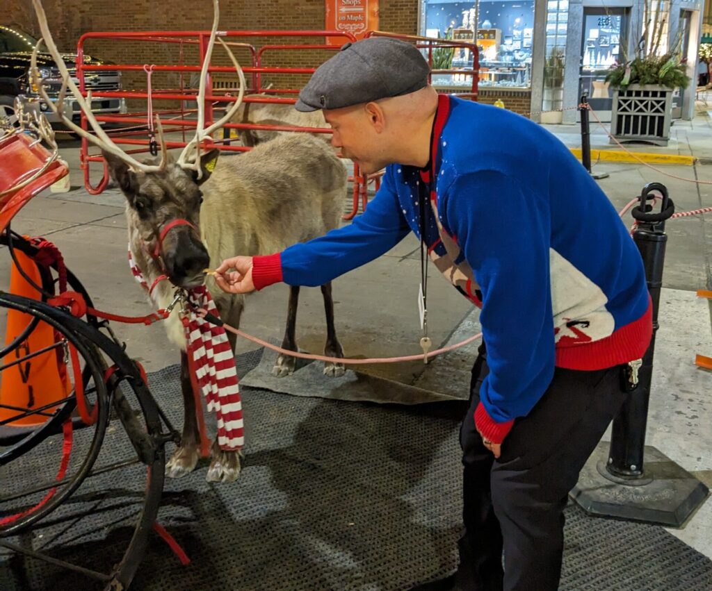 Larry feeding reindeer at jingle in the junction